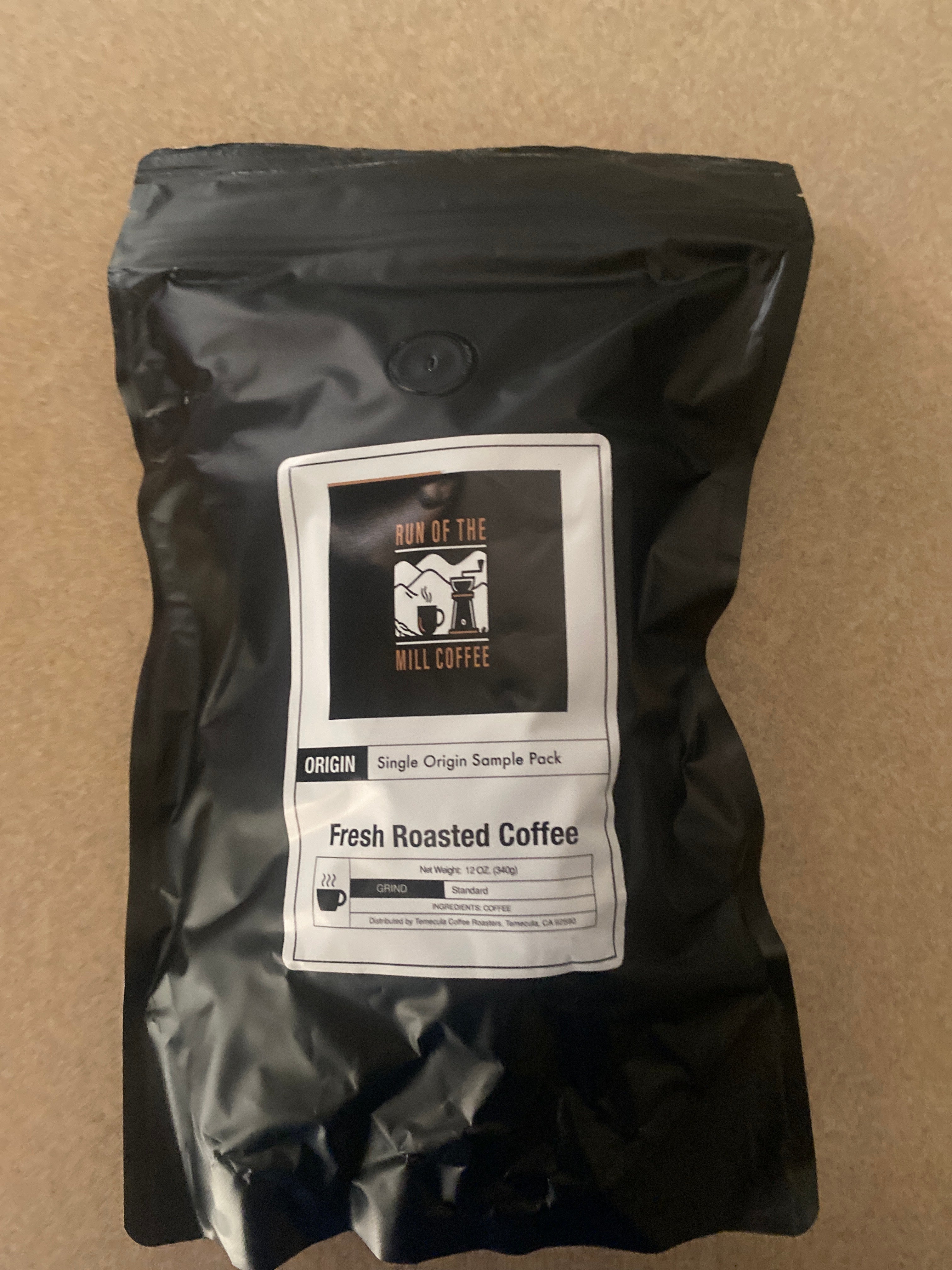 Single Origin Coffee Sample Pack with fresh roasted coffee in a black bag.